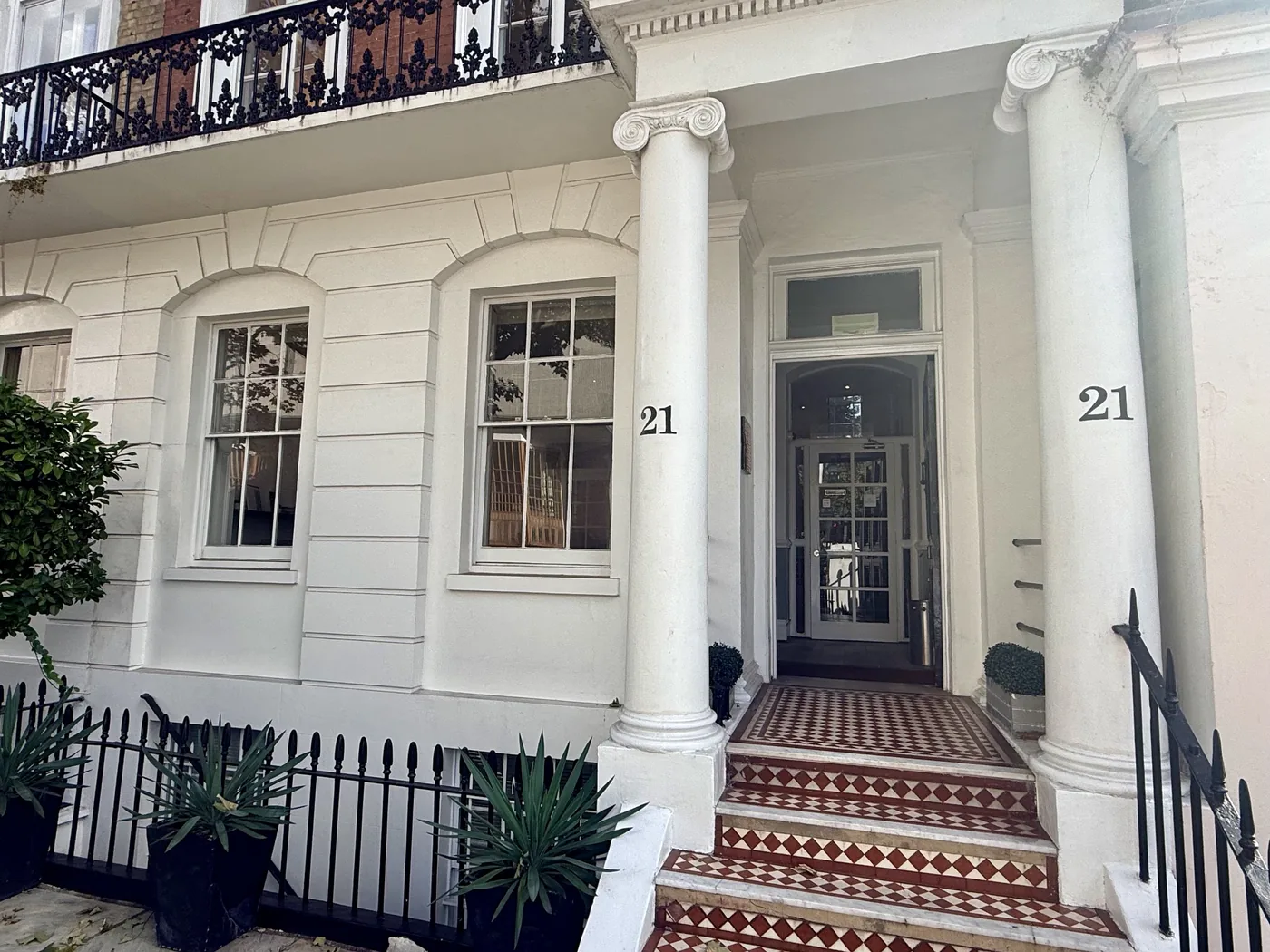 The entrance to Behrens Dental Practice at 21 Thurloe Place, South Kensington, London SW7, with white columns and red and white tiled steps