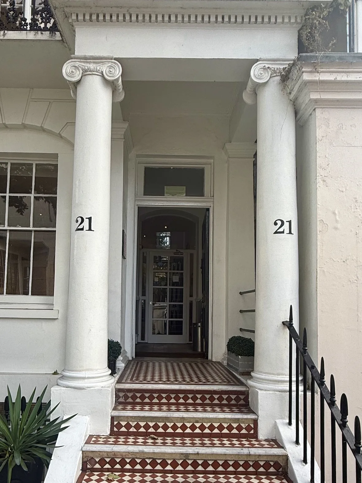The front steps of Behrens Dental Practice at 21 Thurloe Place, South Kensington, London SW7, with red and white tiles leading up between two white columns